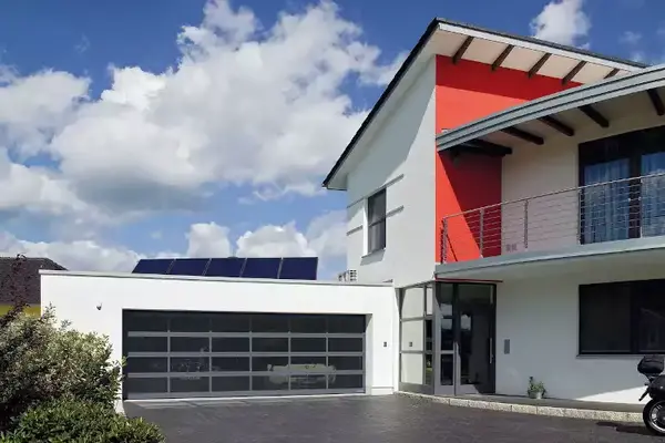Modernes Einfamilienhaus mit Flachdach, großer Garage und Solaranlage auf dem Dach.