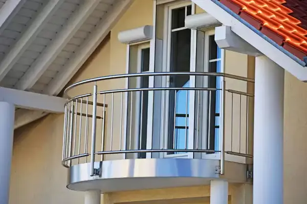 Moderner Balkon mit Edelstahlgeländer an einem Einfamilienhaus mit weißen Fenstern.